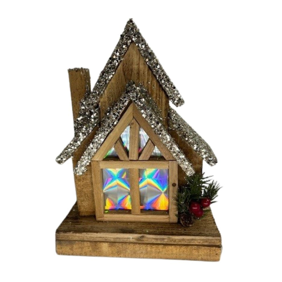 Lighted Bear Mountain Christmas chalet with sparkling roof, colorful windows, evergreen and red berry accents
