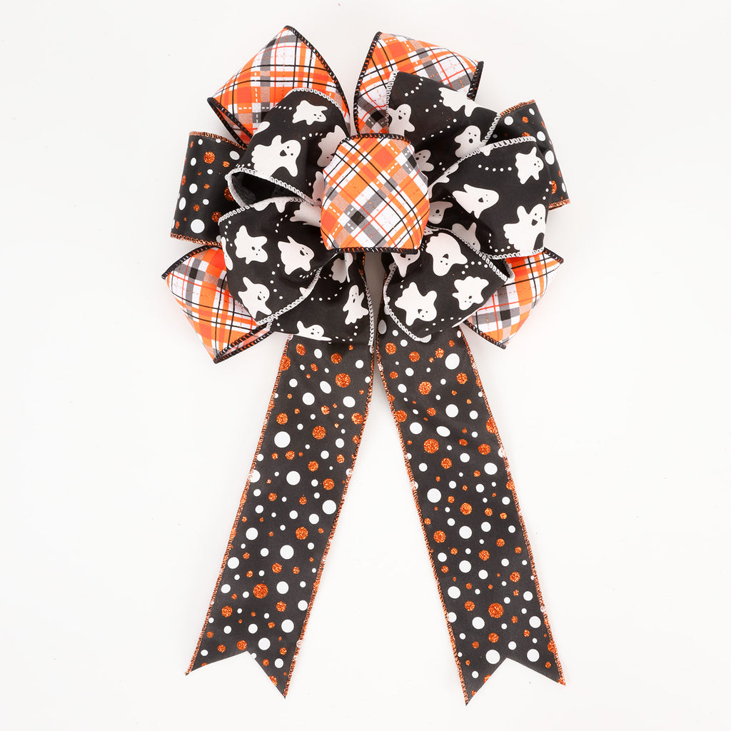 A Halloween-themed decorative bow with two loops and two long tails, featuring black fabric with white ghosts, orange and white plaid, and black with orange and white polka dots, on a plain white background.